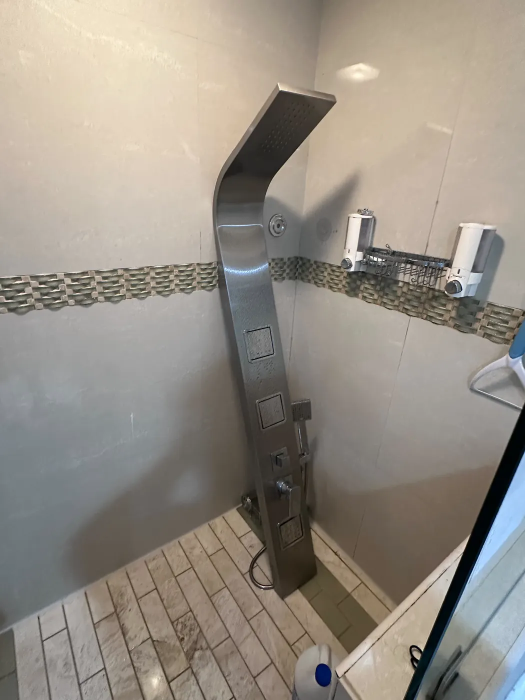 Wider view of the new shower panel and shelves in a tiled walk-in shower